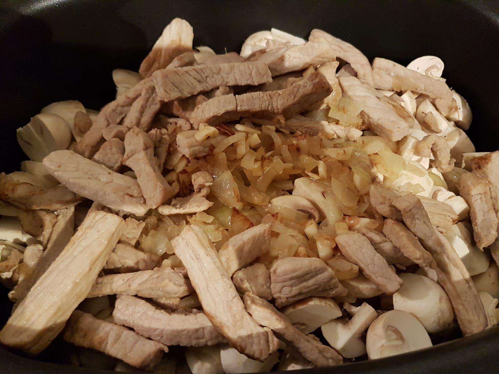 Fleisch, Pilze, Knoblauch und Zwiebeln im Slow Cooker. 