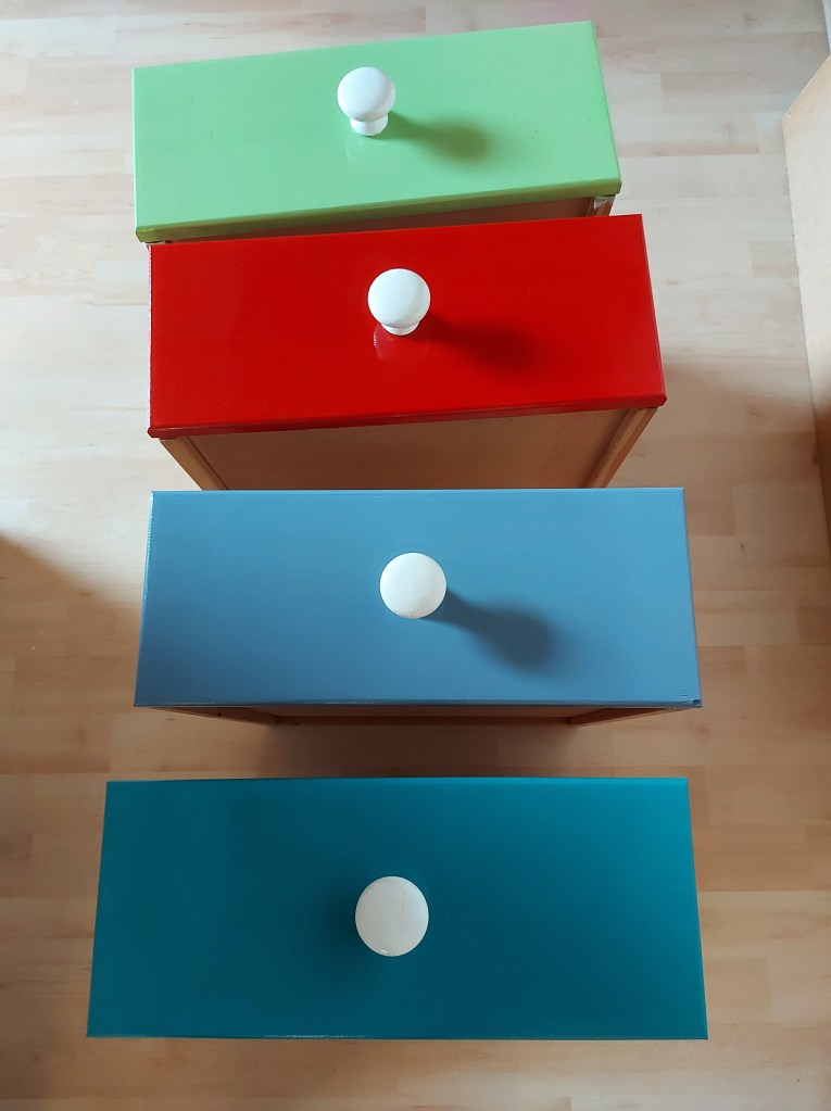 bunt lackierte Schubladen mit weißen Knöpfen